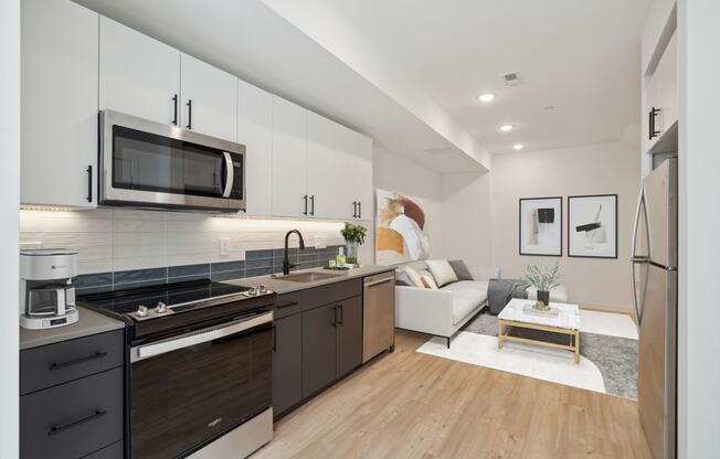 Chic open-concept living room with dark wood kitchen cabinets, stainless steel appliances, and a cozy lounge area with a light sofa, white marble coffee table, and stylish wall art.