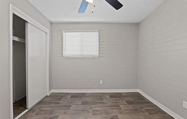 A room with a ceiling fan and a window with blinds.