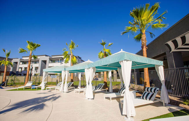 a patio with hammocks and umbrellas and palm trees