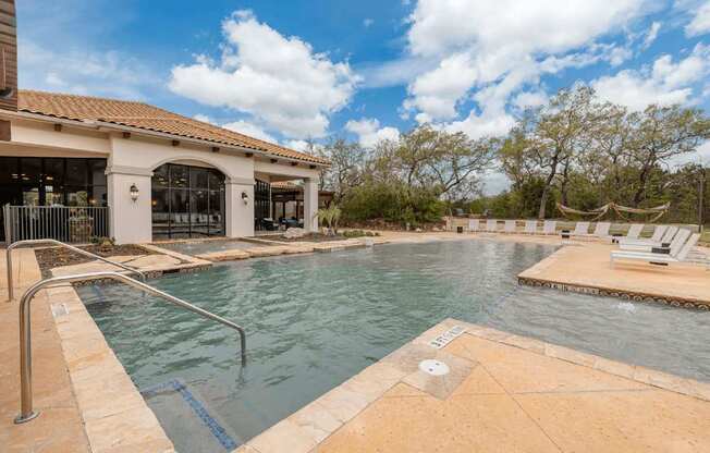 A pool with a metal railing and a building in the background.