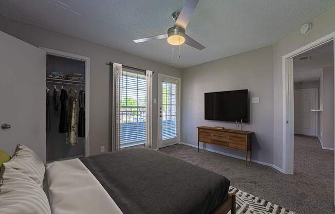 A bedroom with a bed, a dresser, a TV and a ceiling fan.