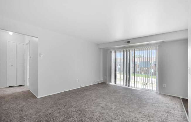 Spacious living room with large windows, neutral walls, and plush carpet at Warren Woods Apartments in Warren, MI.