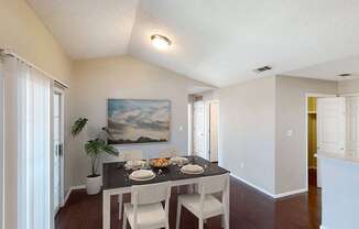 a dining room with a table and chairs and a painting on the wall