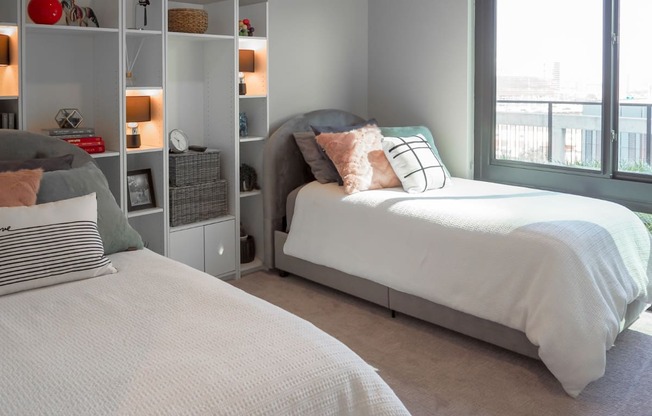 3 bedroom model second bedroom with two twin size beds and a bookcase at The Hamilton apartments in Dallas, TX