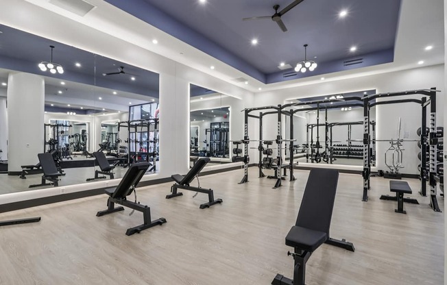A gym with a variety of equipment including weights and benches.