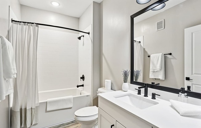 A white bathroom with a toilet, sink, and shower.