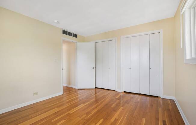 an empty room with wood floors and white closets