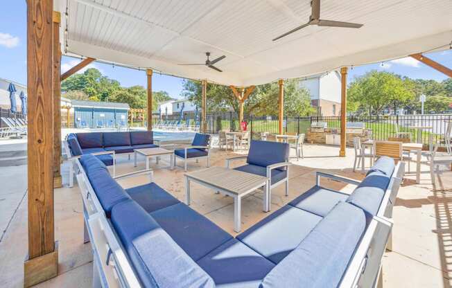 a covered patio with blue couches and tables