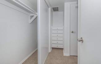 A white door is open to a hallway with a white dresser.