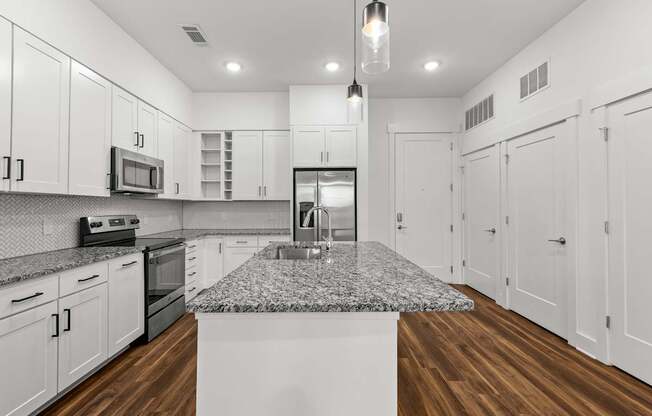 A kitchen with white cabinets and a granite countertop.