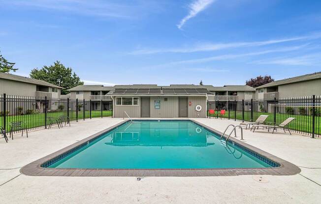 A swimming pool surrounded by a black fence and a building in the background.