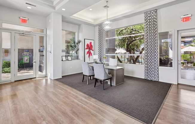 A room with a grey chair and a grey rug in front of a desk.