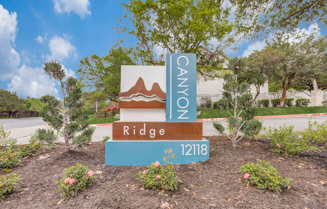 A sign for Canyon Ridge 12118 is in front of a tree.