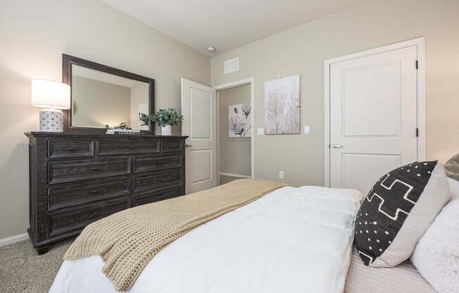 A bedroom with a large bed and a wooden dresser.