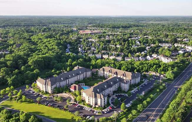 An aerial view of a large apartment complex surrounded by greenery and roads.