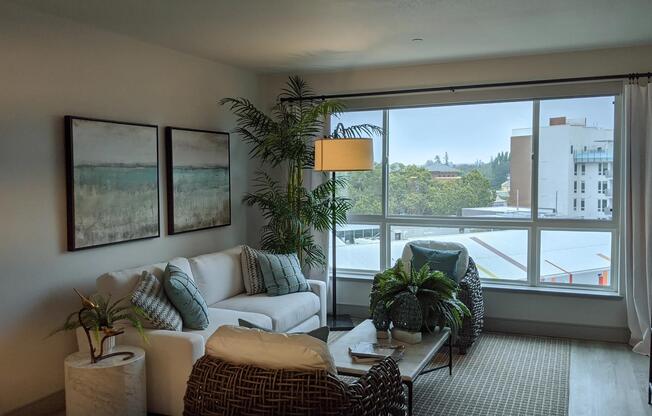 Cozy living area with oversized windows, wood‑style plank flooring, and greenery creating a calming space for everyday comfort.