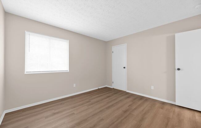 A room with a window and wooden flooring.