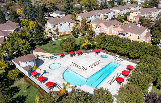 An aerial view of a pool surrounded by trees and buildings.