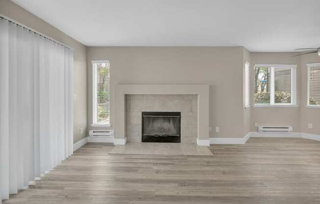 an empty living room with a fireplace and windows