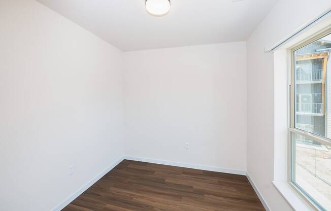 a living room with white walls and wood flooring and two windows at The Crossings at Windsong, Arizona, 86314