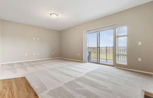 A spacious room with a large rug and sliding glass doors.