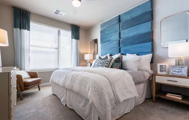 A bedroom with a large bed and a chair.