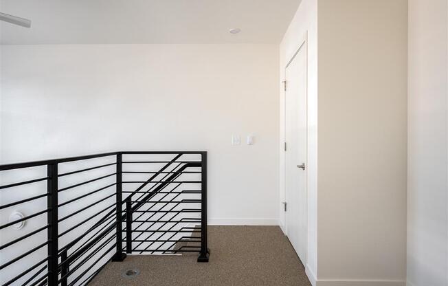 a stairwell in a home with a black railing and white walls