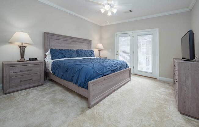 A bedroom with a large bed, a dresser, a nightstand, and a television.