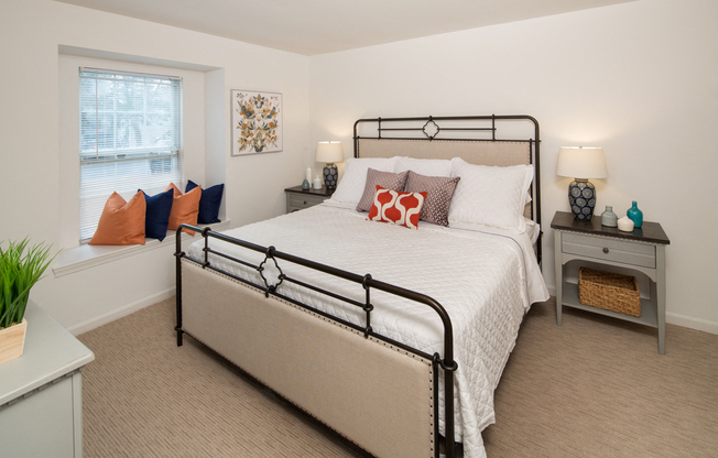 Bedroom with a queen size bed adorned by two nightstands and window with a small nook