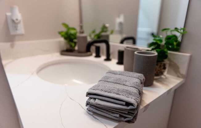 A stack of towels sits on a sink in a bathroom.
