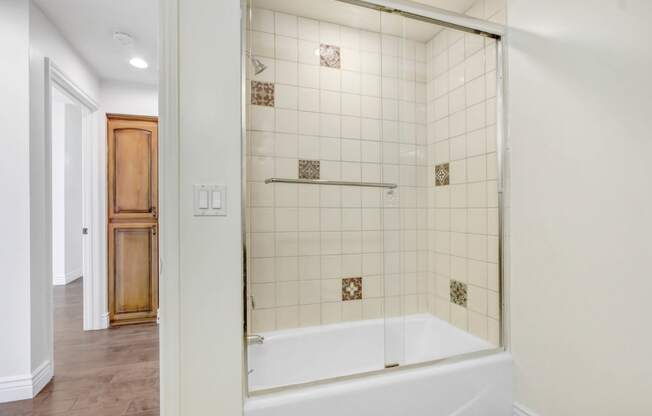 a white tiled bathroom with a tub and a shower