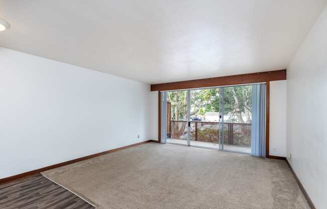 an empty living room with a sliding glass door to a patio