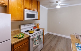 a kitchen with white appliances and wooden cabinets and a counter top with a stove top