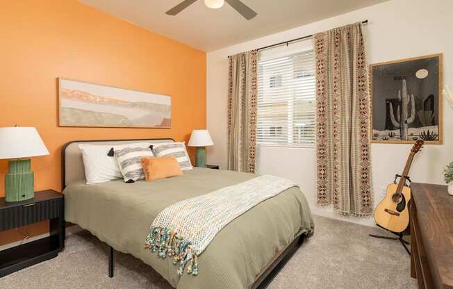 A bedroom with a bed, two lamps, a guitar, and a painting on the wall.