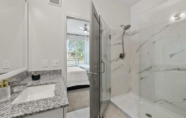 A bathroom with a marble countertop and a walk-in shower.