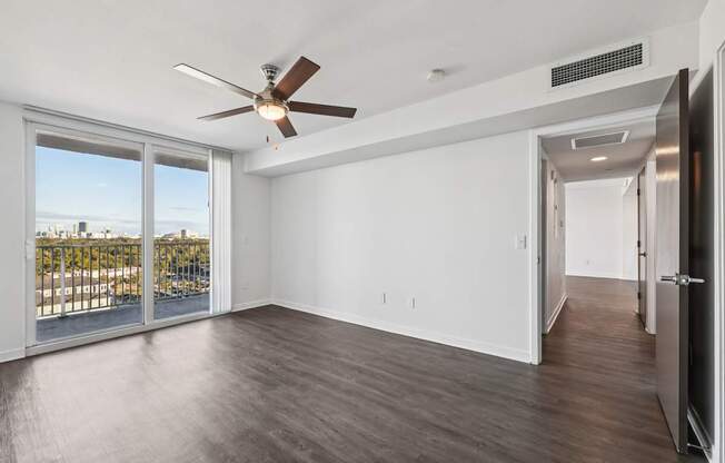 A room with a ceiling fan and sliding glass doors.