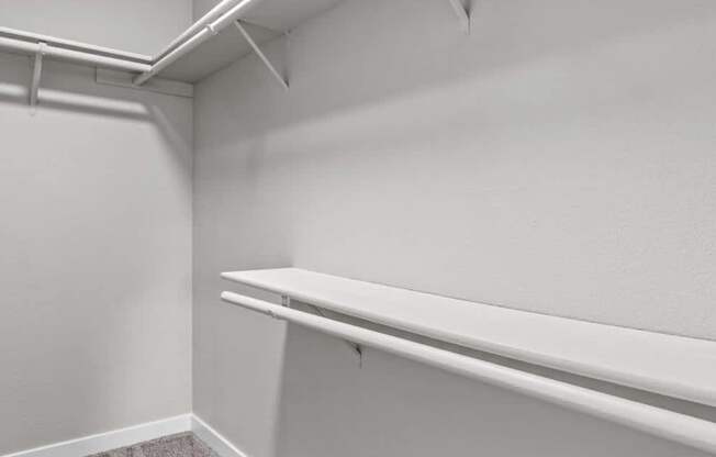 A white closet with two shelves and a hanging rod.