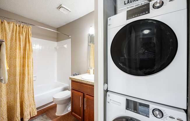 a washer and dryer in a bathroom next to a toilet and a sink