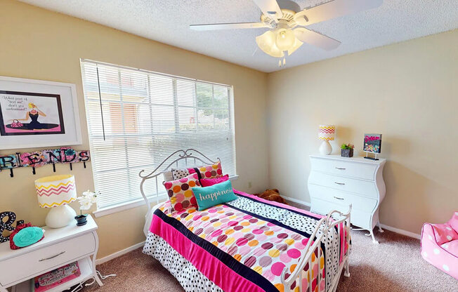 A bedroom with a bed, dresser, and window.