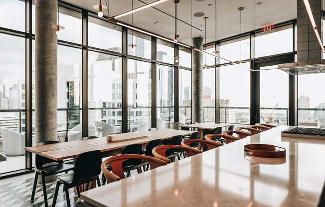 a long table and chairs in a restaurant with large windows at The Lively, Jersey City, NJ 07302