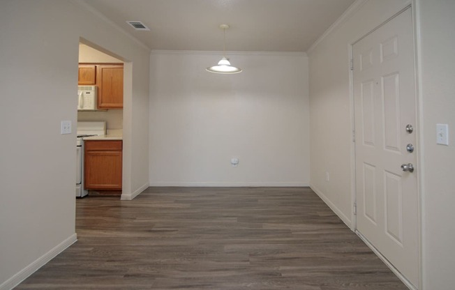 an empty living room with a door to a kitchen