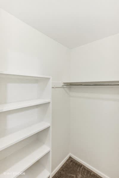 large closet with white shelves and a white wall and