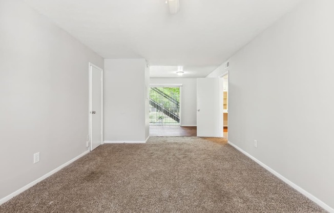 a spacious living room with carpet and white walls