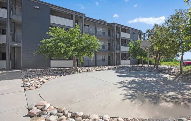 an outdoor area with trees and rocks in front of an apartment building