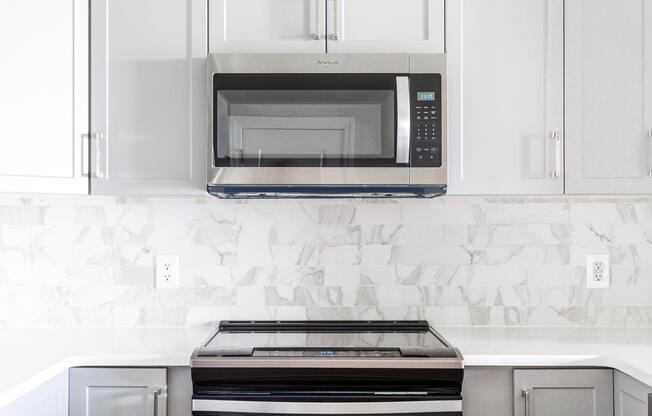 A black microwave oven is mounted above a stove in a kitchen.