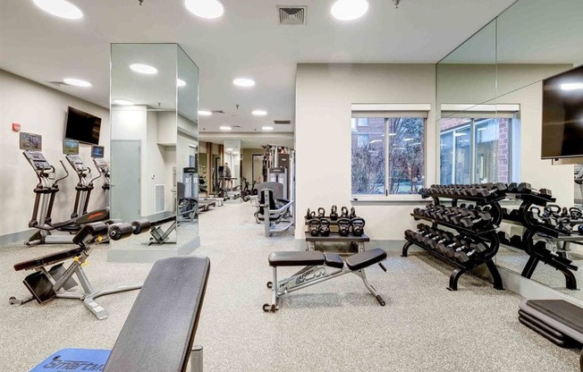 a gym with weights and cardio equipment and mirrors in a building