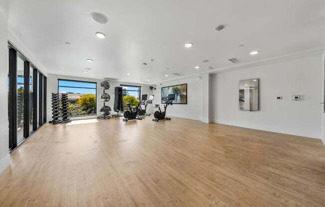 A spacious room with wooden flooring and exercise equipment.