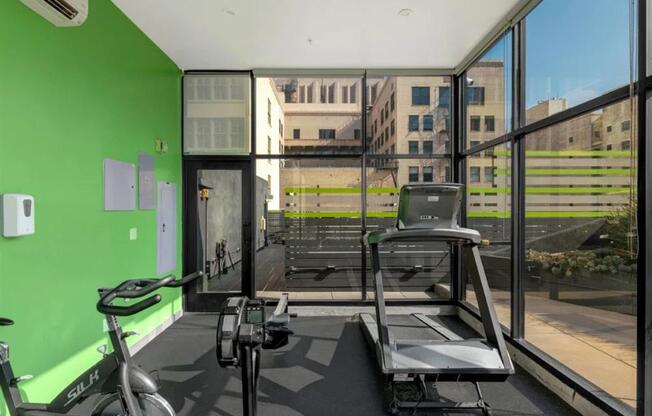 a gym with a treadmill and a bike in front of a window