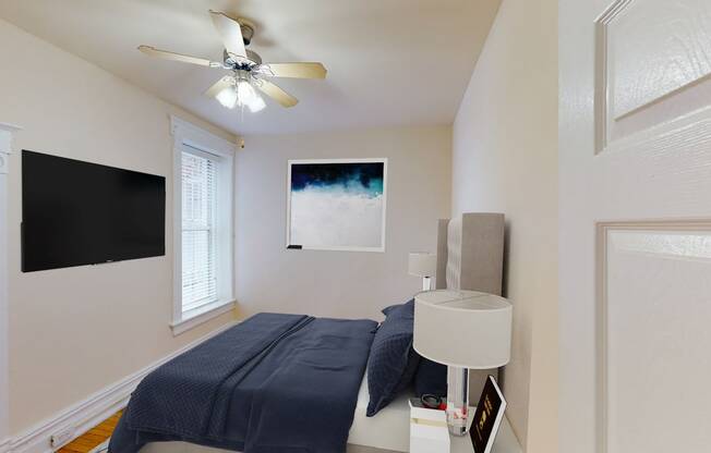 bedroom with bed, tv, nightstand and large window at dupont apartments in washington dc