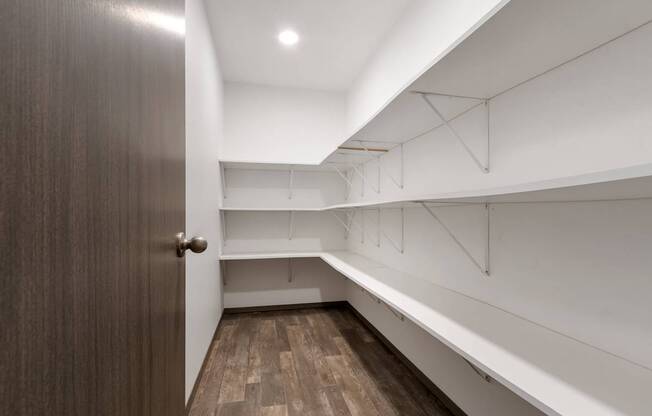 A hallway with a brown door and white walls.